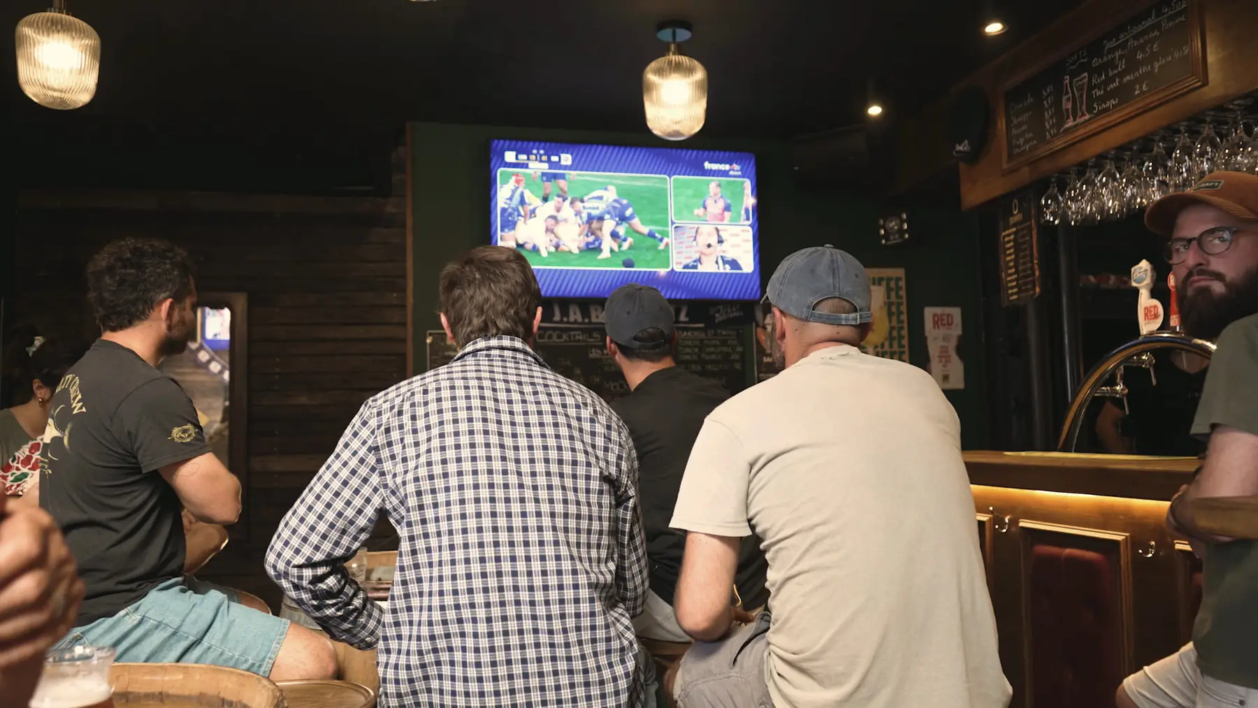 Des clients accoudés au comptoir du Molly’s Pub, un match de rugby à l’écran